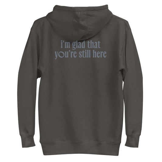 Back view of the dark sweater with the text 'i'm glad that you're still here' printed on it.